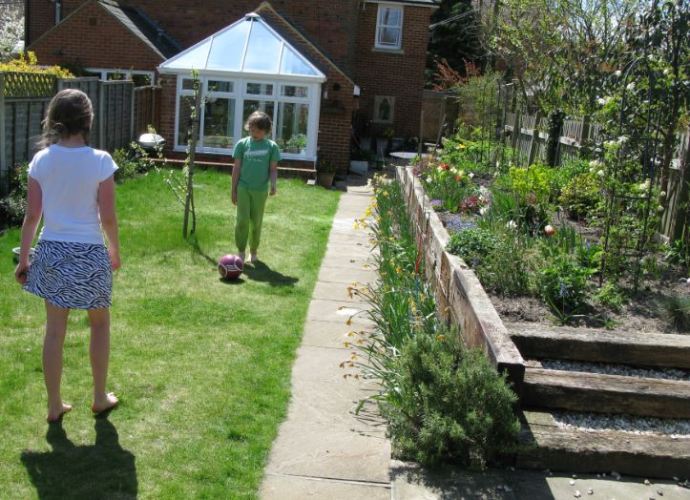 Trädgården är lite för smal för fotboll, men det gör ju att barnen får en ursäkt att hälsa på grannarna då och då... Längst till höger skymtar klematisen på sin klätterställning. Vår fina rad med påskliljor intill gången är nästan helt överblommad.