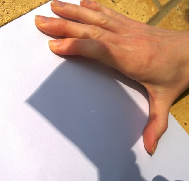 Vi hade gjort små hål i papper som vi lät solen lysa igenom för att få en bild av fenomenet. Här har L tagit kort på min solförmörkelse-projecering. 