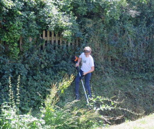 J köpte en trimmer och A hjälper till med röjningen på andra sidan bäcken.